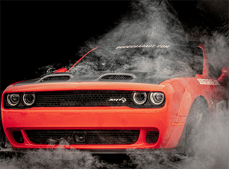 Closeup of orange Dodge Challenger SRT surrounded by smoke
