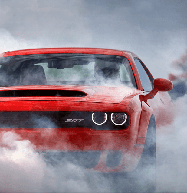 Red Dodge Challenger SRT Hellcat smoking its tires