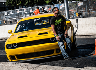Man leaning on a custom yellow Dodge Challenger SRT Hellcat