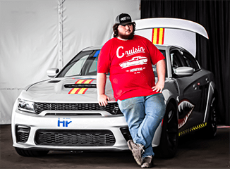 Man leaning on a customized Dodge Charger SRT Hellcat