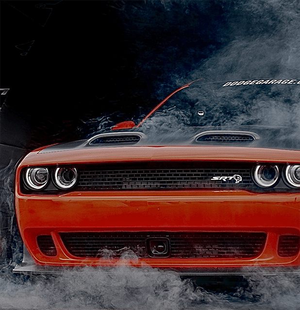 Closeup of orange Dodge Challenger SRT surrounded by smoke