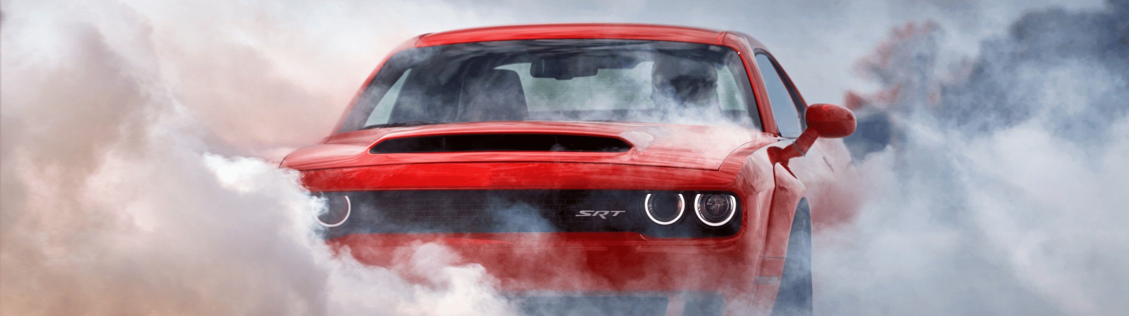 Red Dodge Challenger SRT smoking its tires