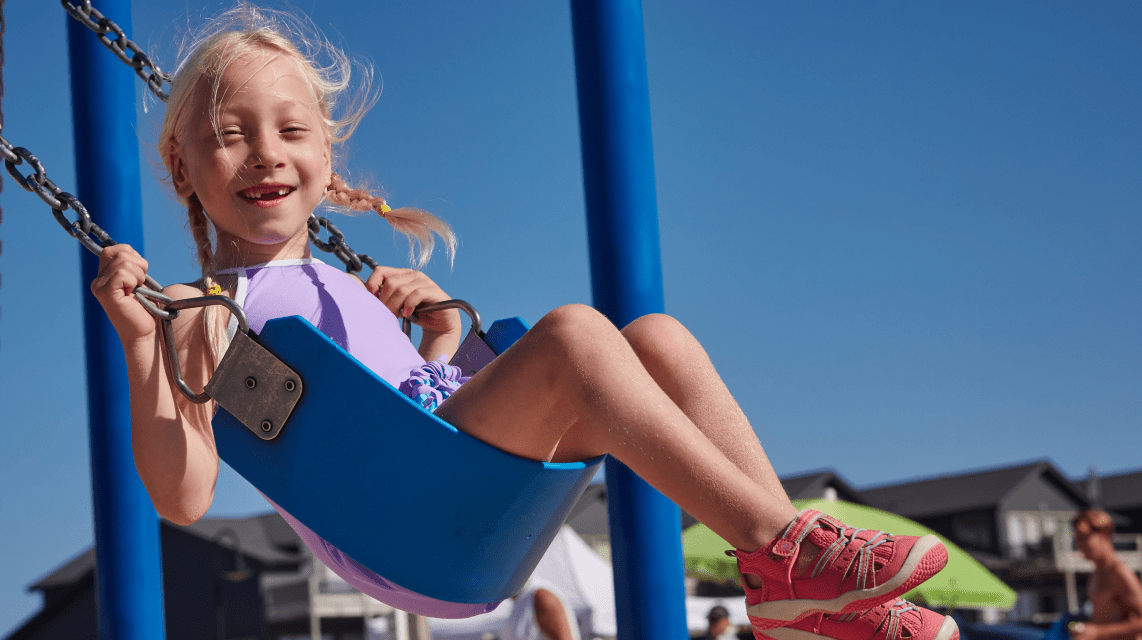 Smiling girl riding playground swing