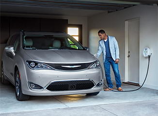 Man plugging charging cable into Chrysler Pacifica Hybrid