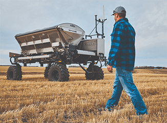 Man approaching large autonomous farming equipment in field