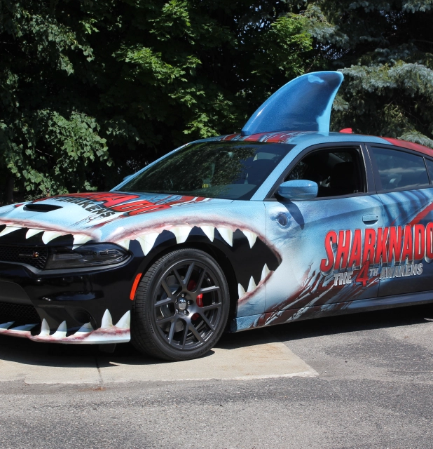 An image of a car wrapped with sharknado branding and a shark fin on the top of the car