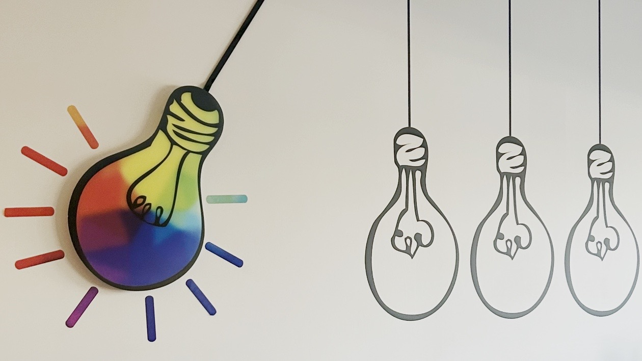 Wall graphics - designed, created and installed by CG Detroit - show a colorful light bulb about to knock some boring black and white light bulbs out of its path.